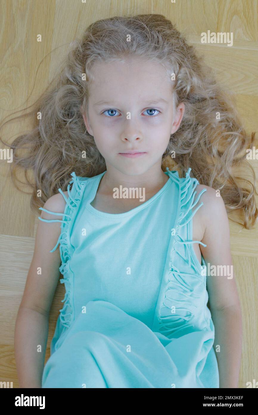 Hübsches kleines Mädchen mit langen, blonden, welligen Haaren und blauen Augen Stockfoto