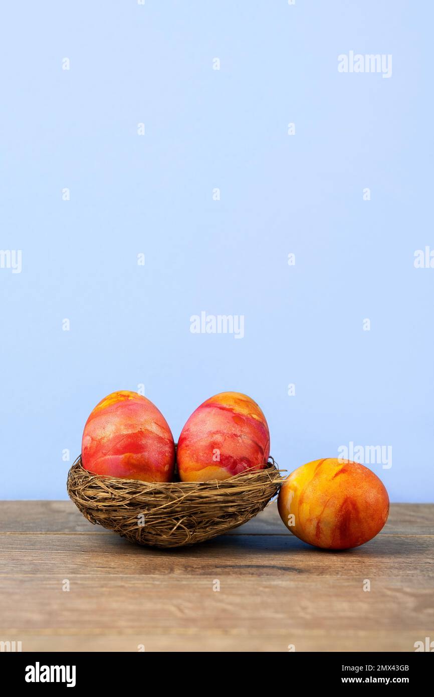 Drei Ostereier in einem dekorativen Sisalnest auf Holzhintergrund. Frohes Osterkonzept. Grußkarte. Stockfoto