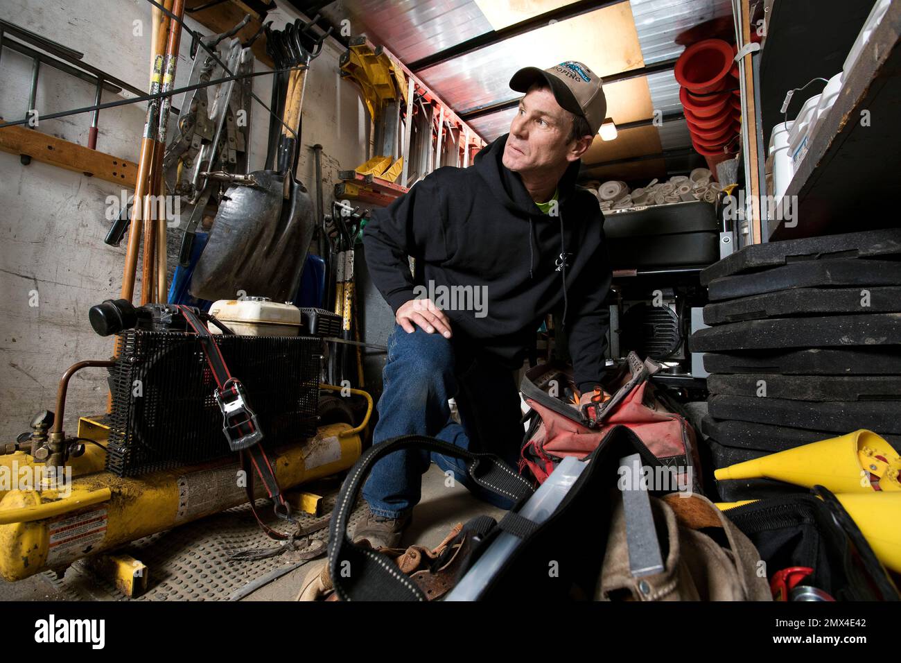 Ein Arbeiter für eine Dachfirma im US-Bundesstaat Michigan auf dem Rücksitz seines Lkws mit Ausrüstung Stockfoto