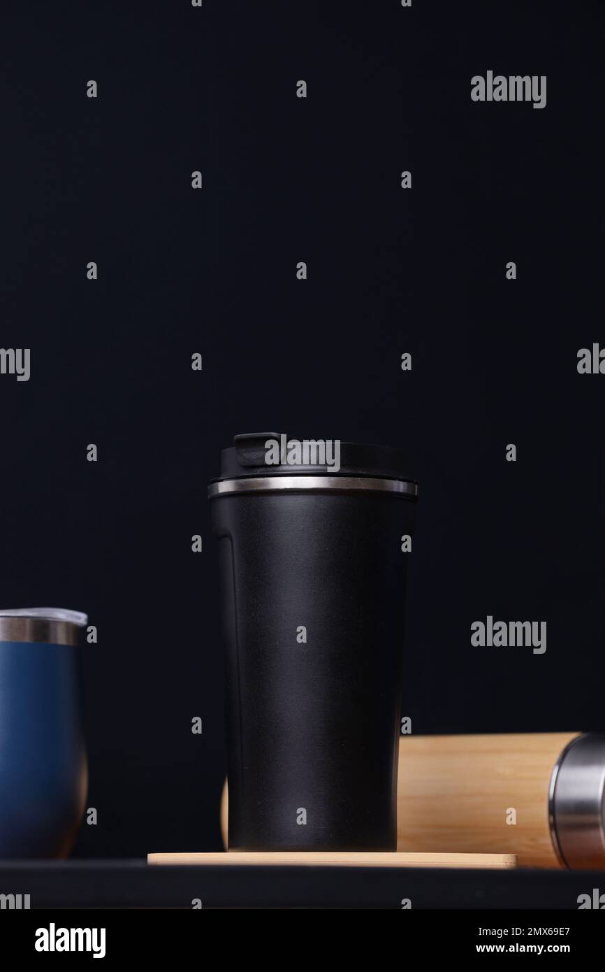Schwarzer Reisebecher aus Metall Nahaufnahme Vorderansicht. Isolierter schwarzer Hintergrund. Ein Reiseabenteuer. Stockfoto
