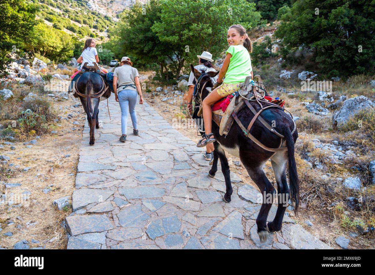 Ein Mädchen reitet einen Esel, um die Höhle von Diktaion Andron zu besuchen. Touristen besuchen die berühmte Höhle Diktaion Andron, den Geburtsort des gottes Zeus auf dem Lasithi Plateau, Cre Stockfoto