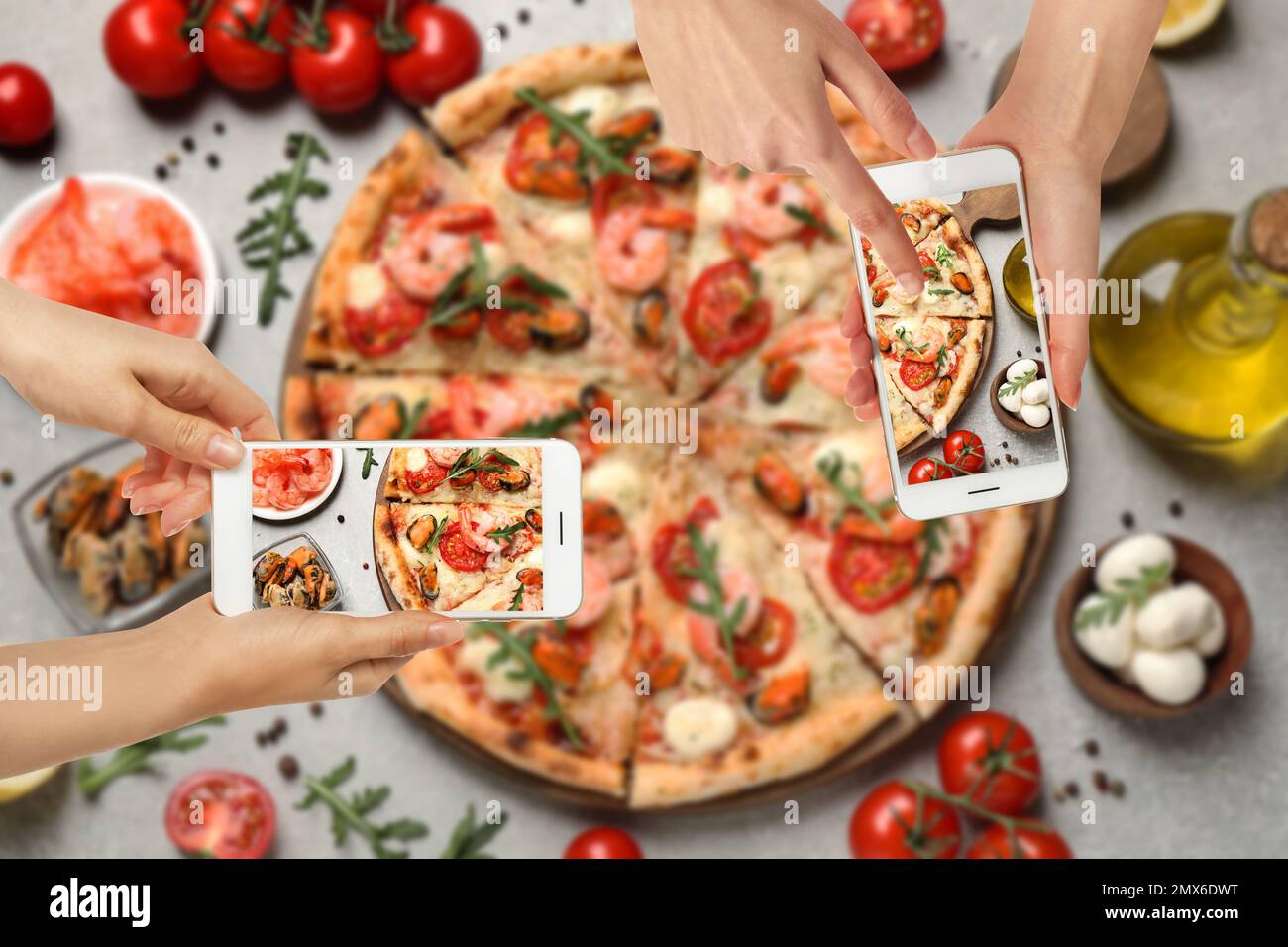 Food-Blogger machen Fotos von köstlicher Meeresfrüchte-Pizza am hellgrauen Tisch, Nahaufnahme Stockfoto