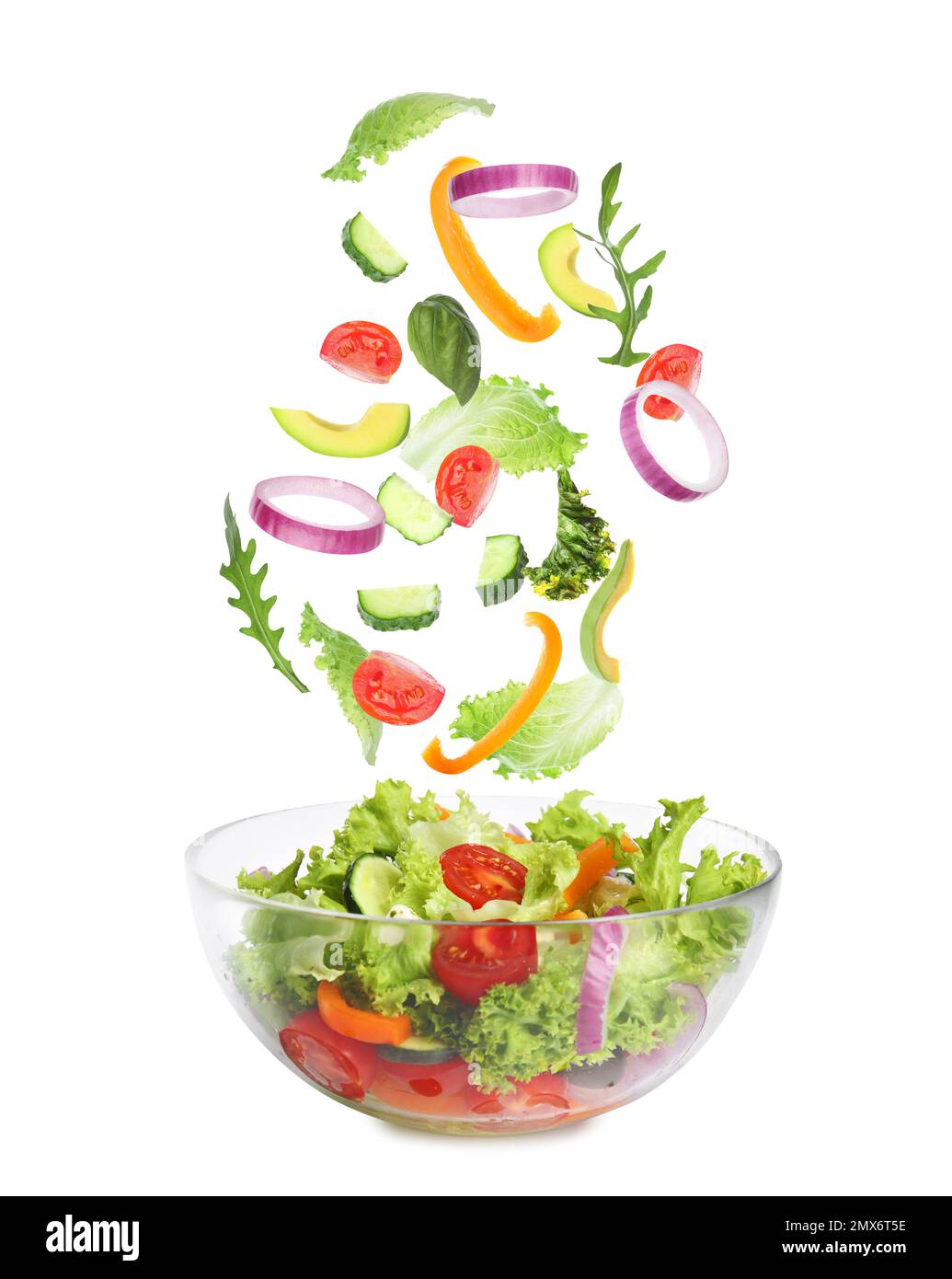 Frische Zutaten für leckeren Salat, der auf weißem Hintergrund in die Schüssel fällt Stockfoto