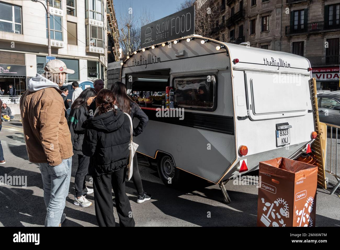 Barcelona, Spanien - 21. Januar 2023: Klassischer Wohnwagen, der für den Verkauf von Fast Food auf der Straße angepasst wurde, mit mehreren wartenden Menschen Stockfoto