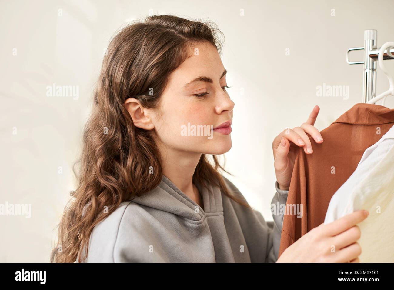 Gebrauchte Kleidung an Kleiderbügeln. Die Frau sucht sich Kleidung im Laden aus Stockfoto