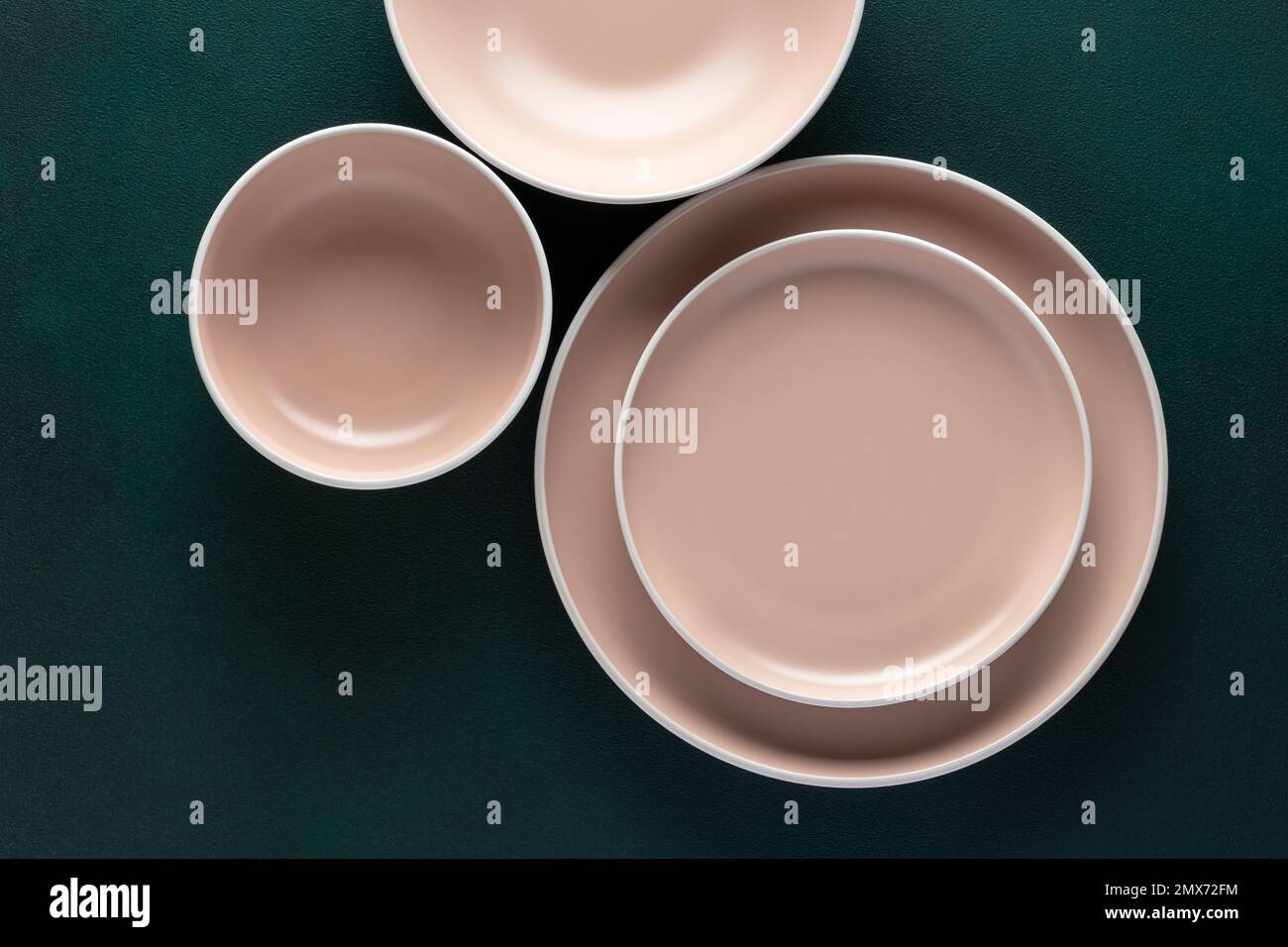 Drei leere beige Platten auf einem dunkelgrünen Tisch, Grunge-Hintergrund. Draufsicht. Karten- oder Menüvorlage, flach liegend, minimalistisches Design. Geschirr, Geschirr Stockfoto