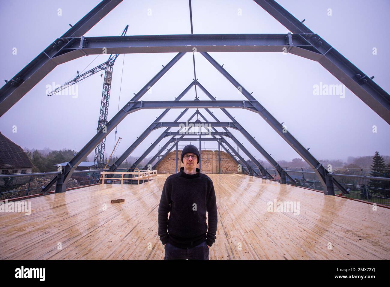 Teplitz, Deutschland. 26. Januar 2023. Der Gründer von Nordwolle, Marco Scheel, steht auf der Zwischendecke aus Holz in der Scheune aus Feldstein, die derzeit umgebaut wird. In den kommenden Monaten werden hier die Workshops zur Herstellung nachhaltiger Funktionsbekleidung aus Wolle von Pommerischen Schafen eingerichtet. Im Jahr 2018 zog Scheel sein Unternehmen, das er zwei Jahre zuvor auf der Insel Rügen gegründet hatte, nach Teplice und war in den Medien für seinen Kampf gegen die Behörden um notwendige Baugenehmigungen bekannt geworden. Kredit: Jens Büttner/dpa/Alamy Live News Stockfoto