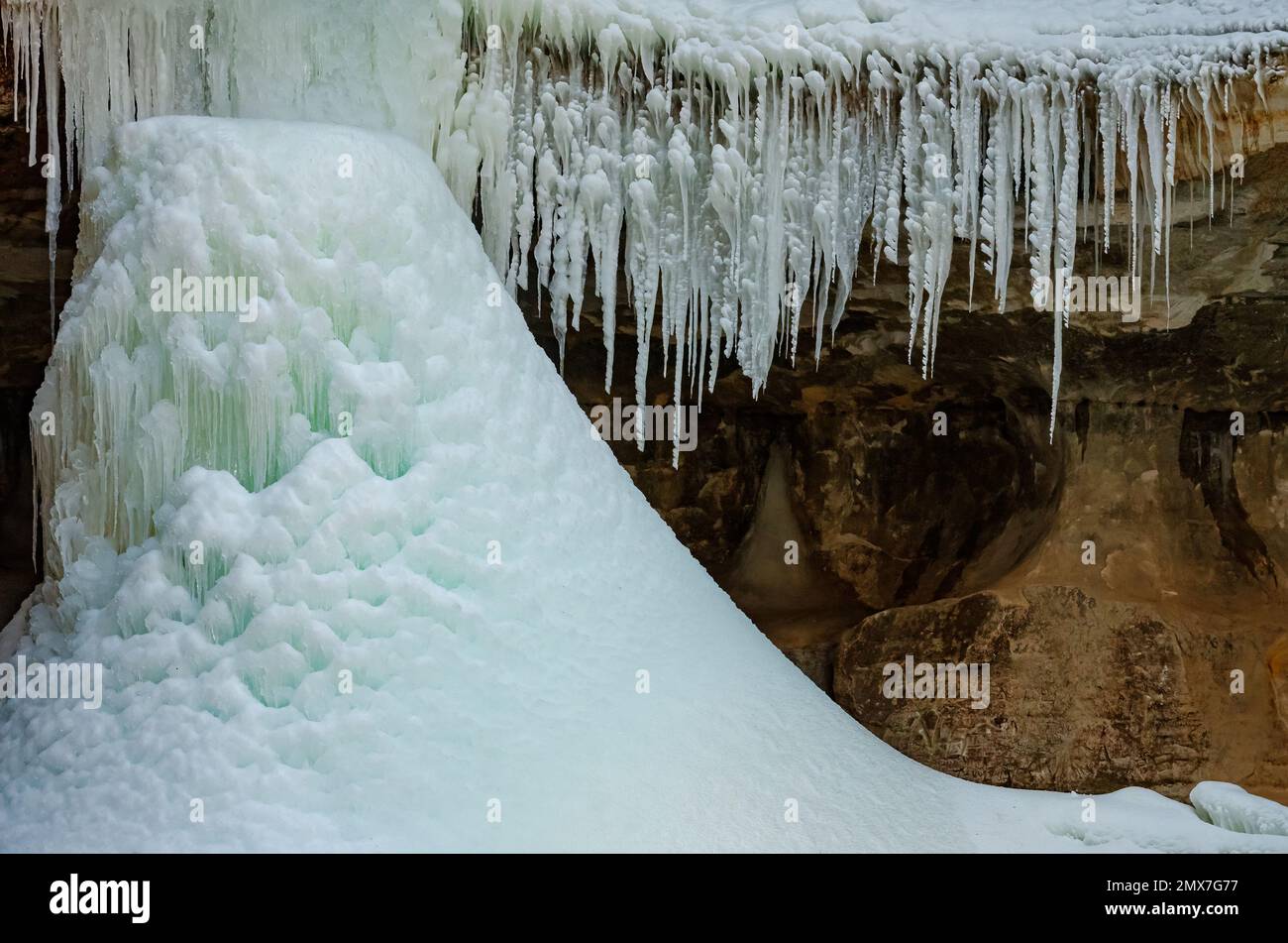 Der Boden eines Eisfalls wird von einem Eiszapfenvorhang eingerahmt. Kaskaskia Canyon, Starved Rock State Park, LaSalle County, Illinois Stockfoto
