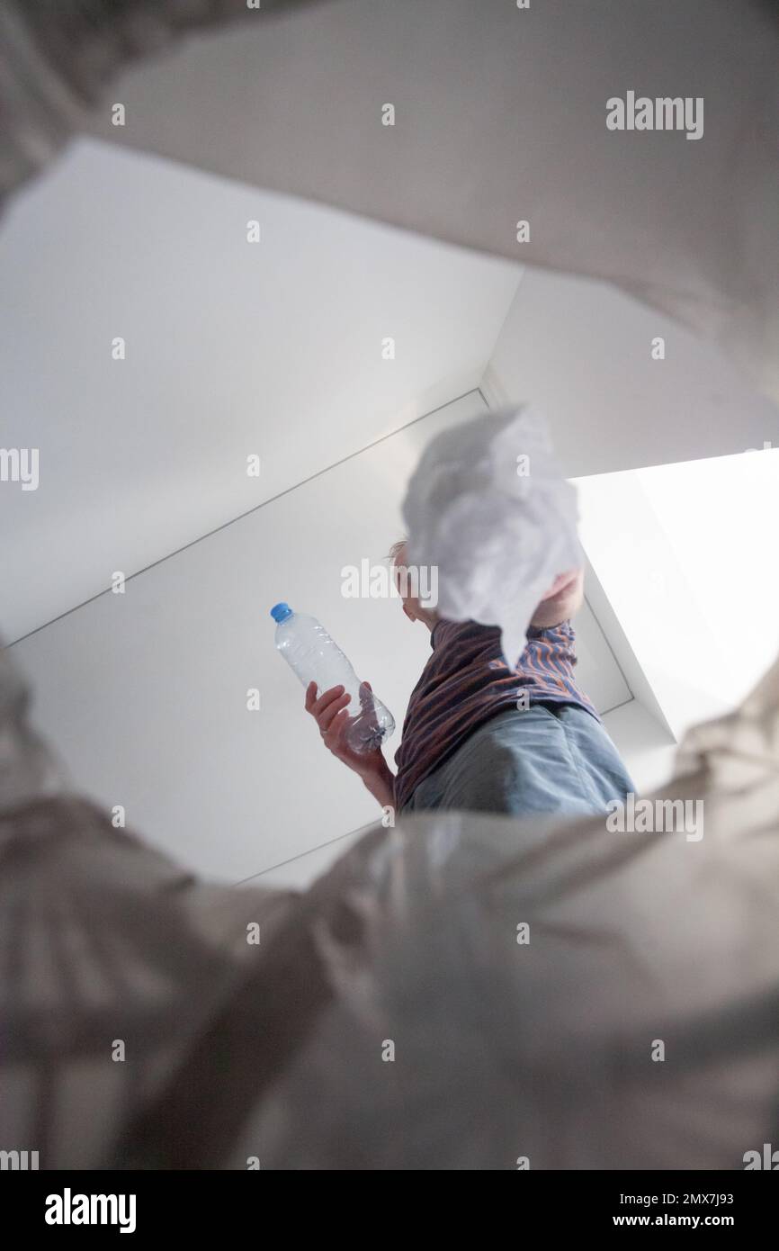 Mann mit Papierserviette und Plastikflasche, die den Abfall zu Hause trennt Stockfoto