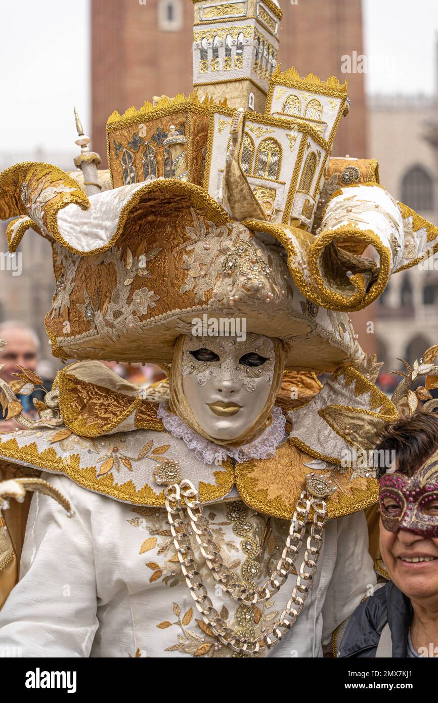 Karneval in Venedig. Ein Mann in einem Karnevalskostüm eines Königs mit einem Stab und einem riesigen Kunstmütze mit venezianischen Häusern auf der Straße in Venedig. Stockfoto