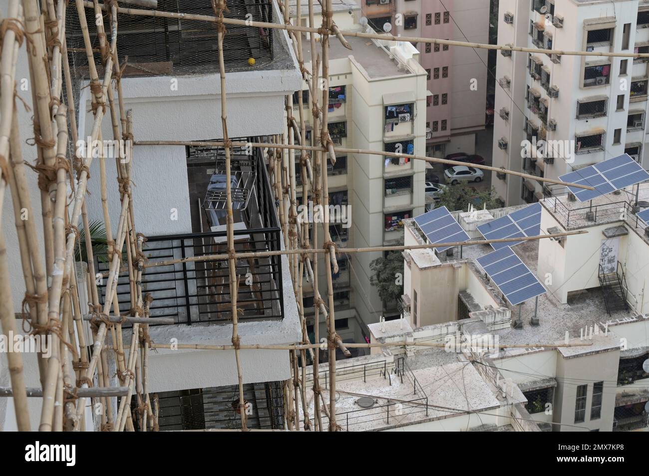 INDIEN, Mumbai, Wohnturm wird gerade renoviert, Bambusgerüst, Sonnenkollektor auf dem Dach / INDIEN, Mumbai, Wohnhaus mit Baugerüst aus Bambus, Solarmodul auf Dach Stockfoto