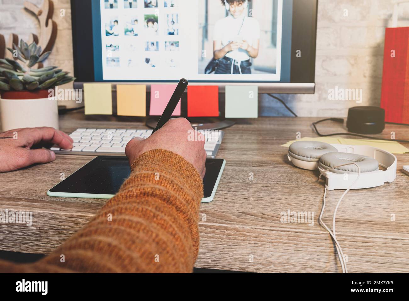 Junger Hipster-Fotograf, der im modernen Büro mit einem digitalen Grafiktablett arbeitet, professioneller Retourenticker, der mit Holz an einem modernen Arbeitsplatz sitzt Stockfoto