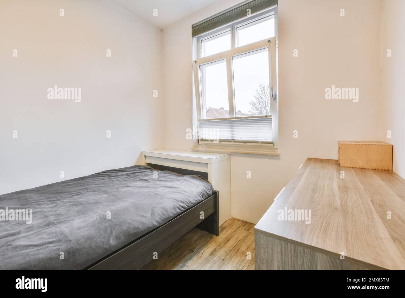Weiße Innenausstattung des Schlafzimmers mit komfortablem Bett und grauer Decke Stockfoto
