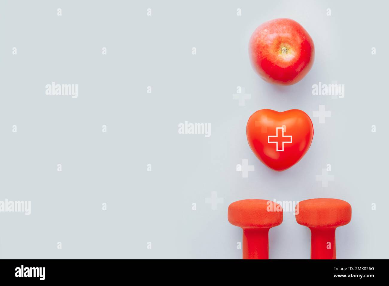 Mit rotem Herz Formen Sie den Hand-Übungsball, den Apfel und die Kurzhanteln auf blauem Hintergrund. Gesundheit, gesunde Ernährung und Sportkonzept, Weltherztag. Flachla Stockfoto
