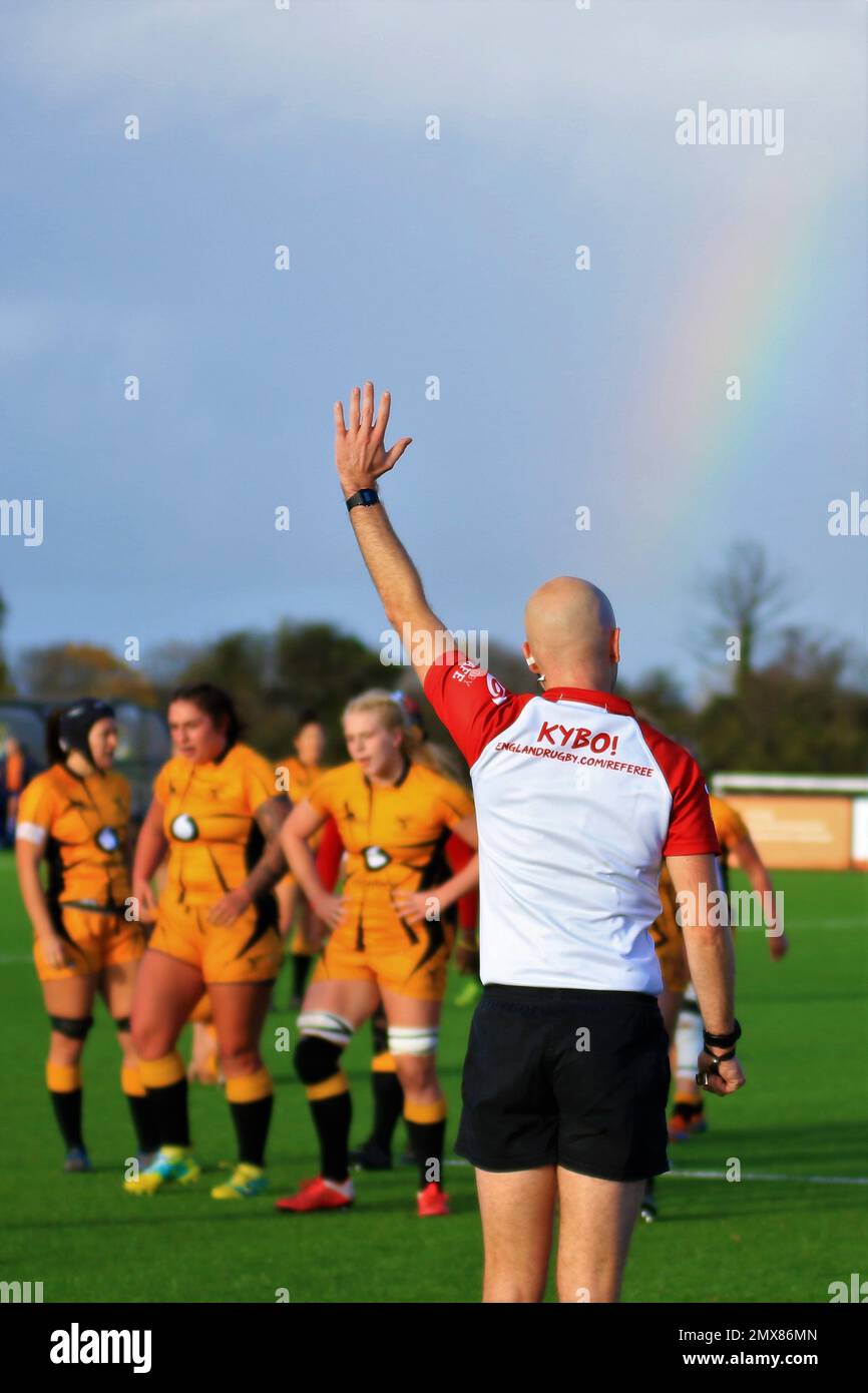 Englischer Rugby-Schiedsrichter in Aktion auf der Allianz Premier 15s mit einem Regenbogen im Hintergrund Stockfoto