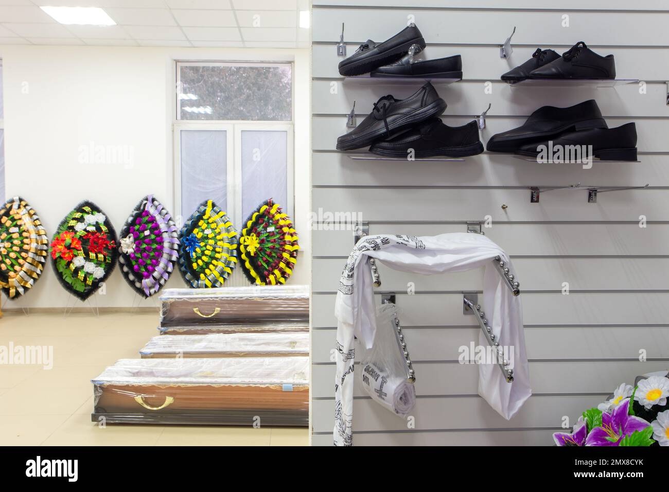 Zimmereinrichtung mit Bestattungszubehör. Ein Laden, der Särge, Grabkränze, Blumen und Schuhe verkauft. Stockfoto