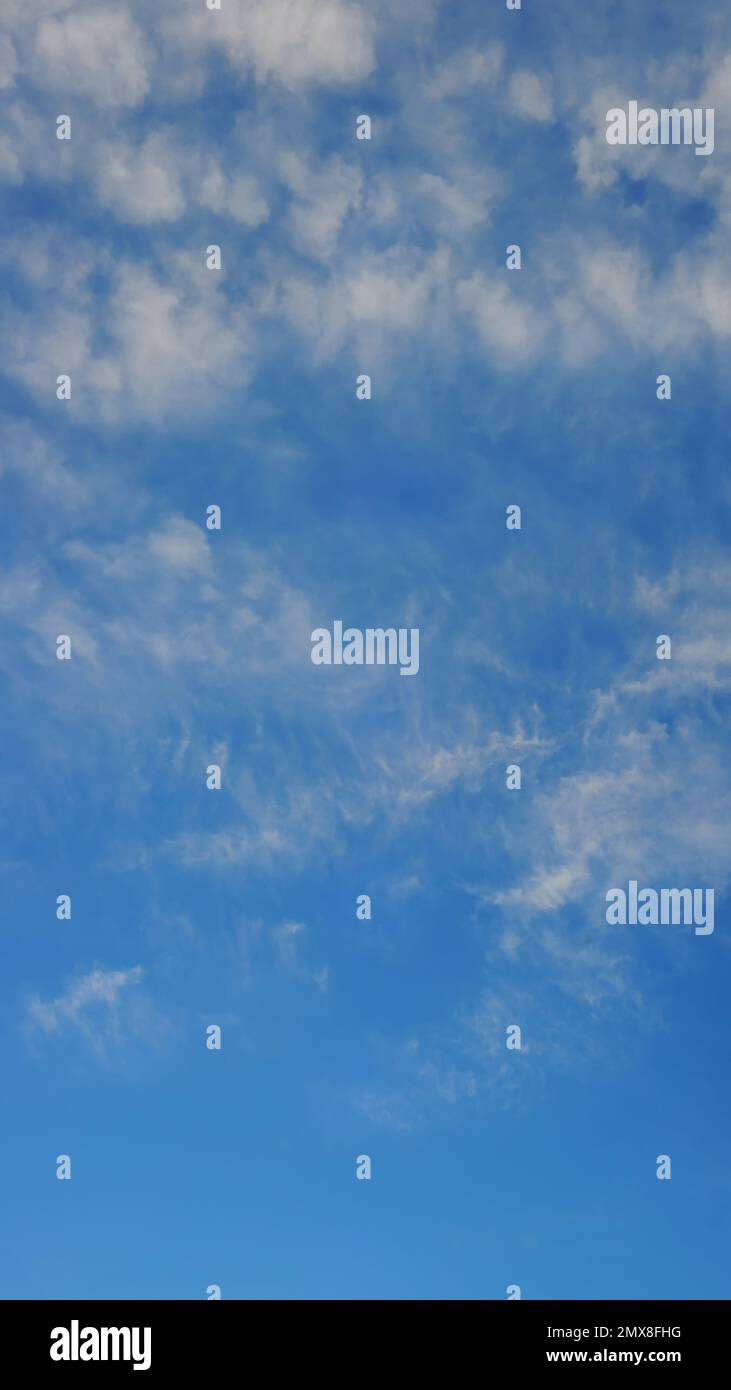 Vertikales Panorama eines blauen Himmels mit hellen Sommerwolken. Hintergrund für den Telefonbildschirm Stockfoto