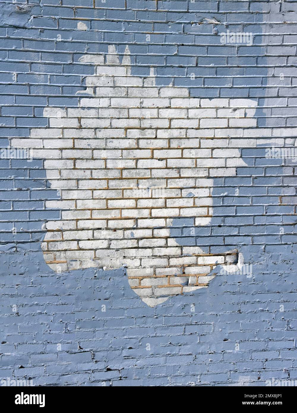 Das Hintergrundbild zeigt eine Backsteinwand, die babyblau gestrichen ist, mit einem weißen Bereich, der blau gestrichen werden muss. Stockfoto