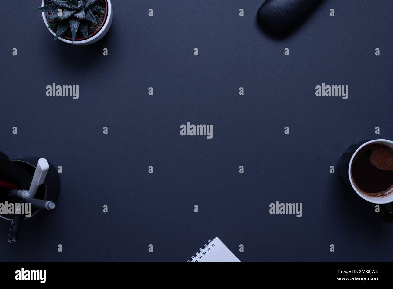 Professioneller schwarzer Schreibtisch mit Pflanzen, Stiften, Kaffeetasse, Brillenbox und Pad. Ansicht von oben, flache Laienkonstruktion für Kopien oder Produktpräsentationen Stockfoto