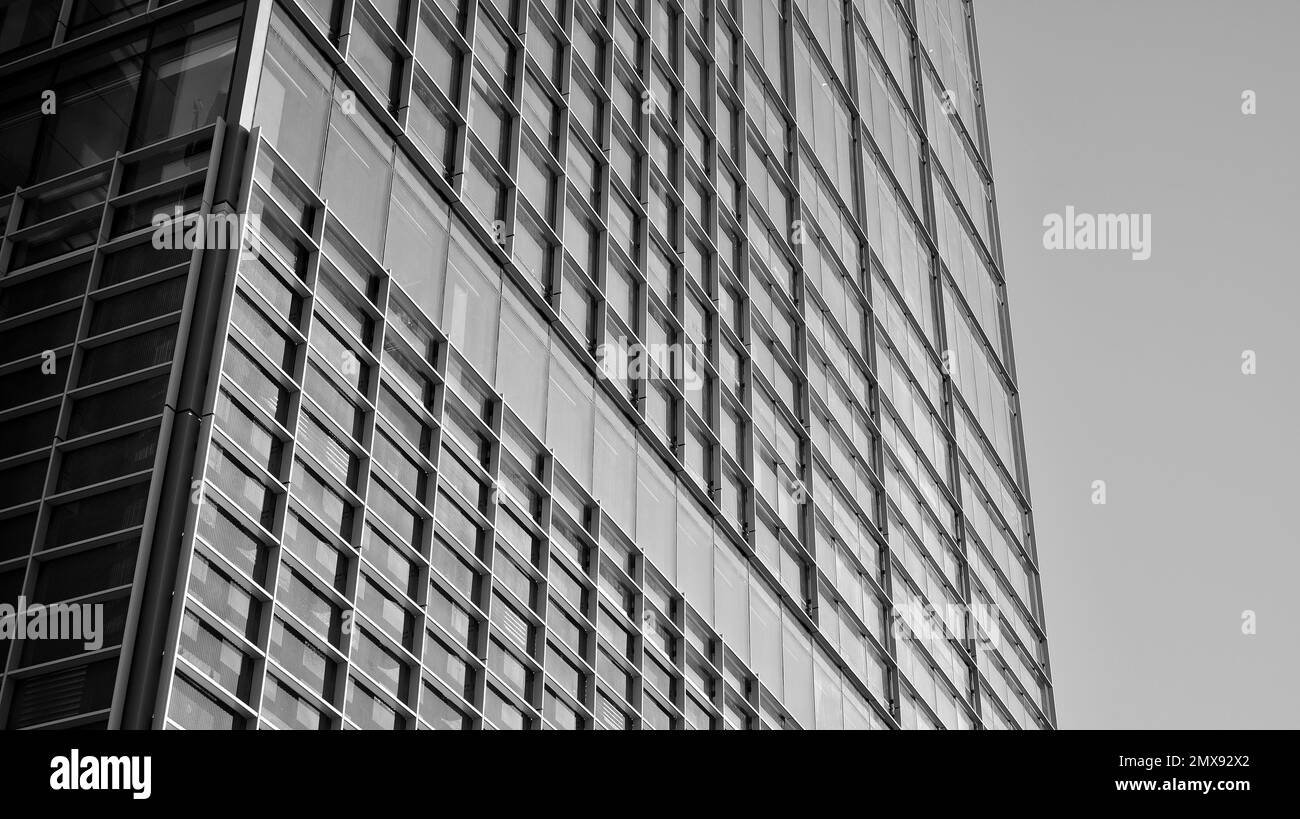 Geschäftsgebäude in blauer Farbe. Gigantischer Wolkenkratzer von unten. Architekturdetails des modernen Gebäudes und Glasfassade. Schwarz auf Weiß. Stockfoto