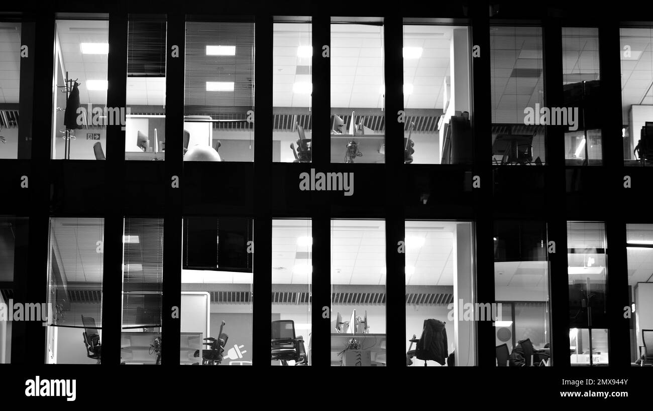 Muster der Fenster von Bürogebäuden, die nachts beleuchtet werden. Beleuchtung mit Glasarchitektur und Fassadendesign mit Reflexion in der Stadt. Schwarz auf Weiß. Stockfoto