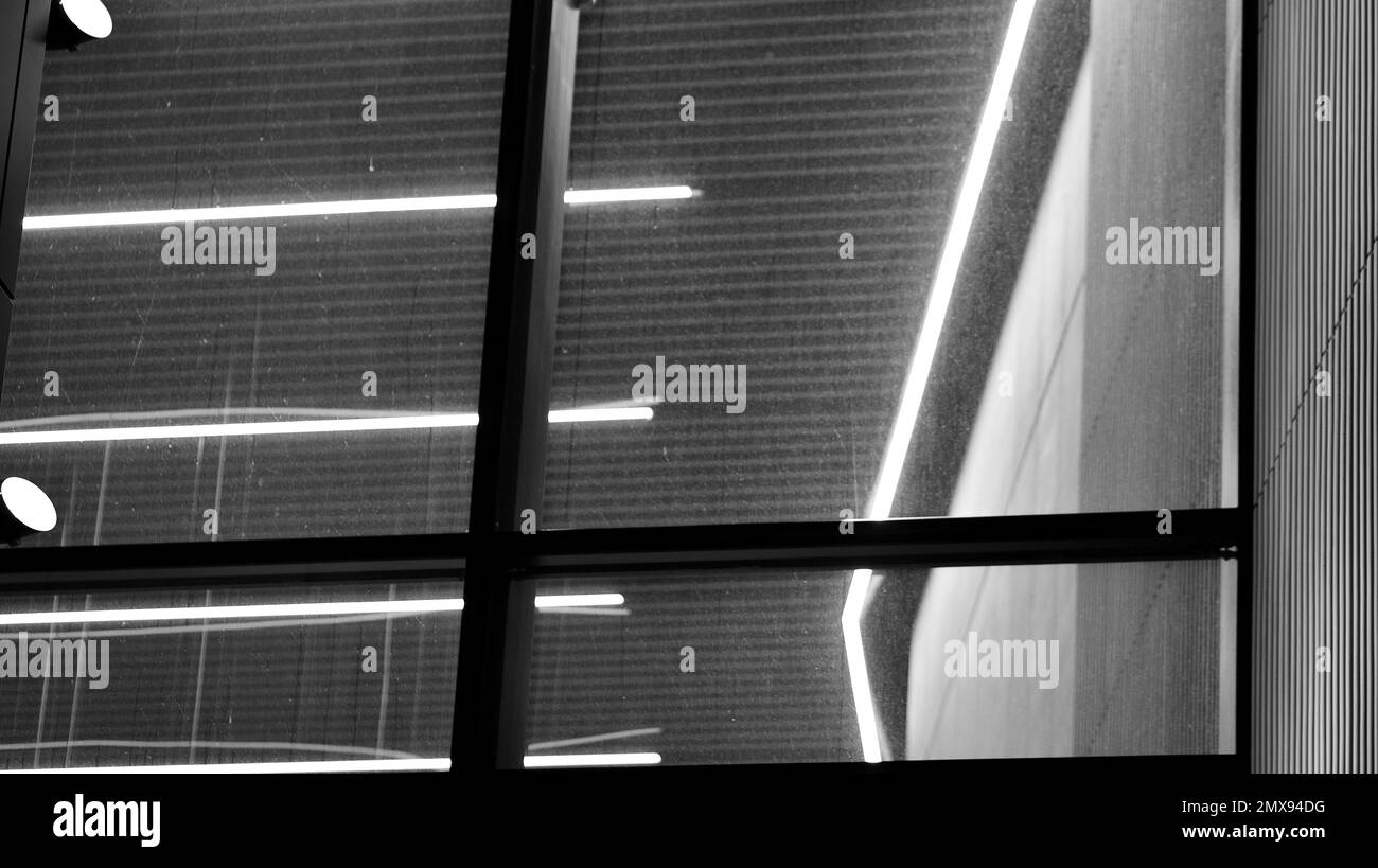 Muster der Fenster von Bürogebäuden, die nachts beleuchtet werden. Beleuchtung mit Glasarchitektur und Fassadendesign mit Reflexion in der Stadt. Schwarz auf Weiß. Stockfoto