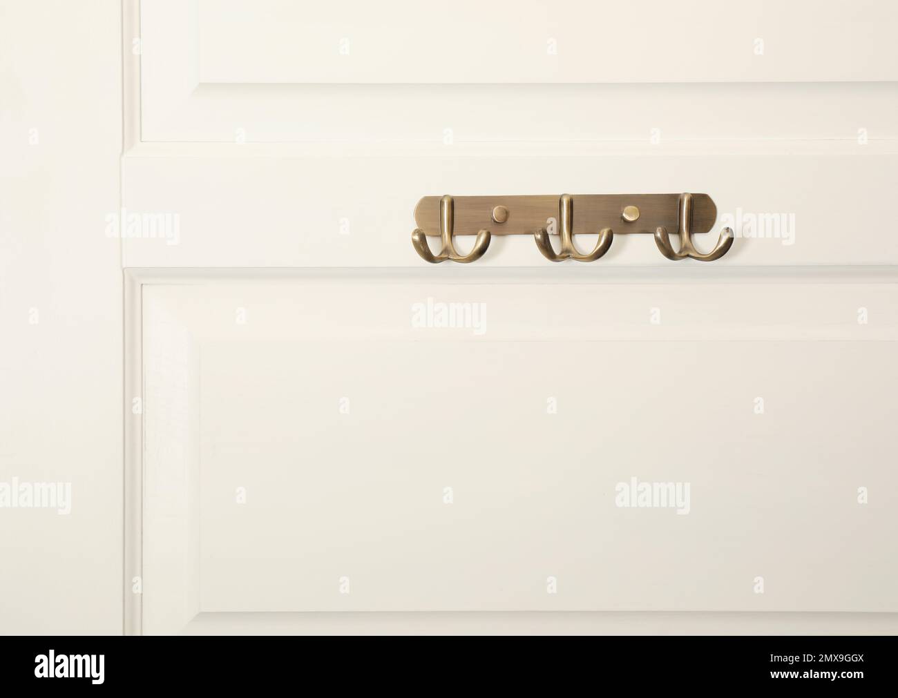 Weiße Tür mit leeren Kleiderhaken aus Metall Stockfoto