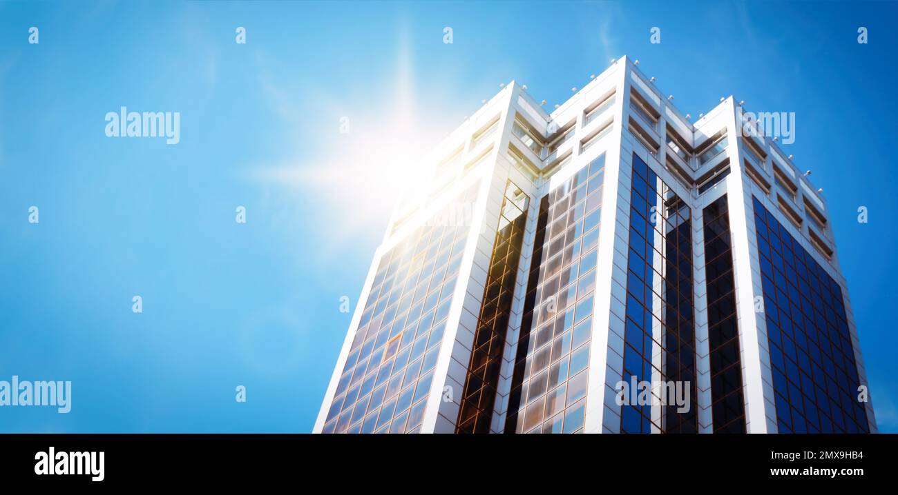 Moderner Wolkenkratzer mit getönten Fenstern vor blauem Himmel, Blick aus niedrigem Winkel. Bauunternehmen Stockfoto