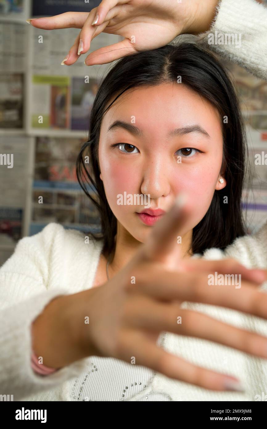 Nahaufnahme eines wunderschönen asiatischen Mädchens mit Händen, die das Gesicht umrahmen Stockfoto