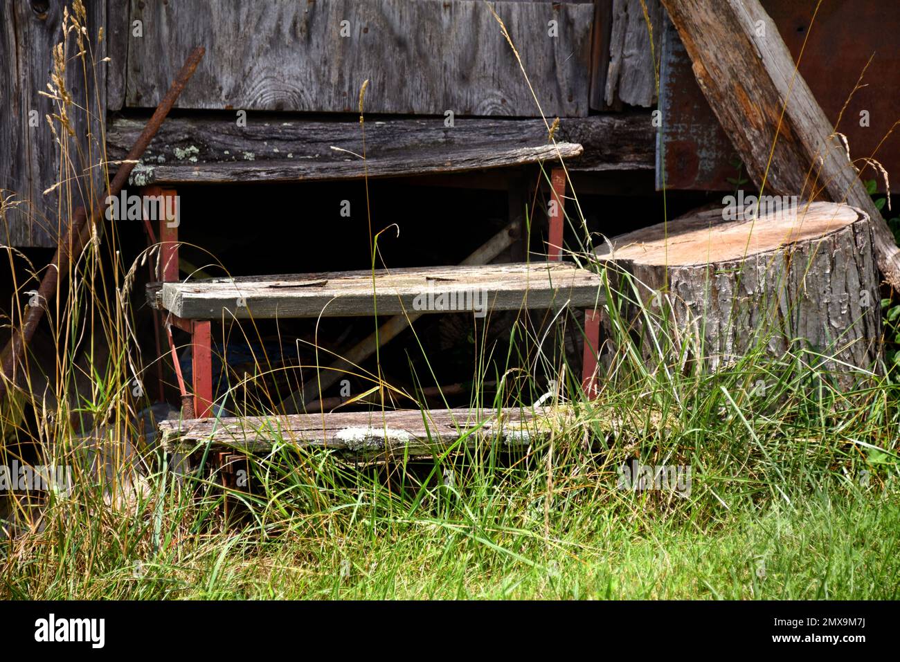 Diese rustikalen Holztreppen bestehen aus drei Ebenen. Die roten Metallstützen heben jeden Holzstamm an den Stufen an. Stockfoto