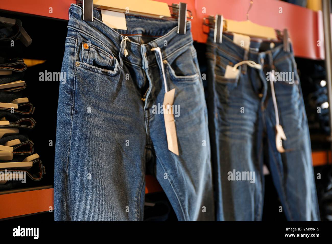 Moderne Jeans, die im Geschäft im Regal hängen Stockfoto