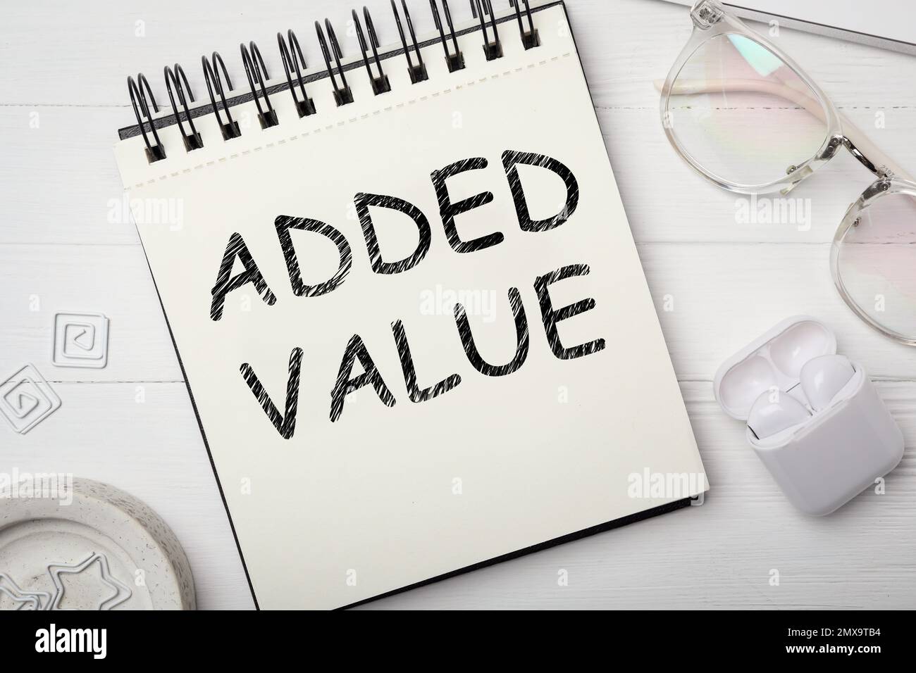 Mehrwert-Konzept. Flache Liegezusammensetzung mit Schreibwaren auf weißem Holztisch Stockfoto