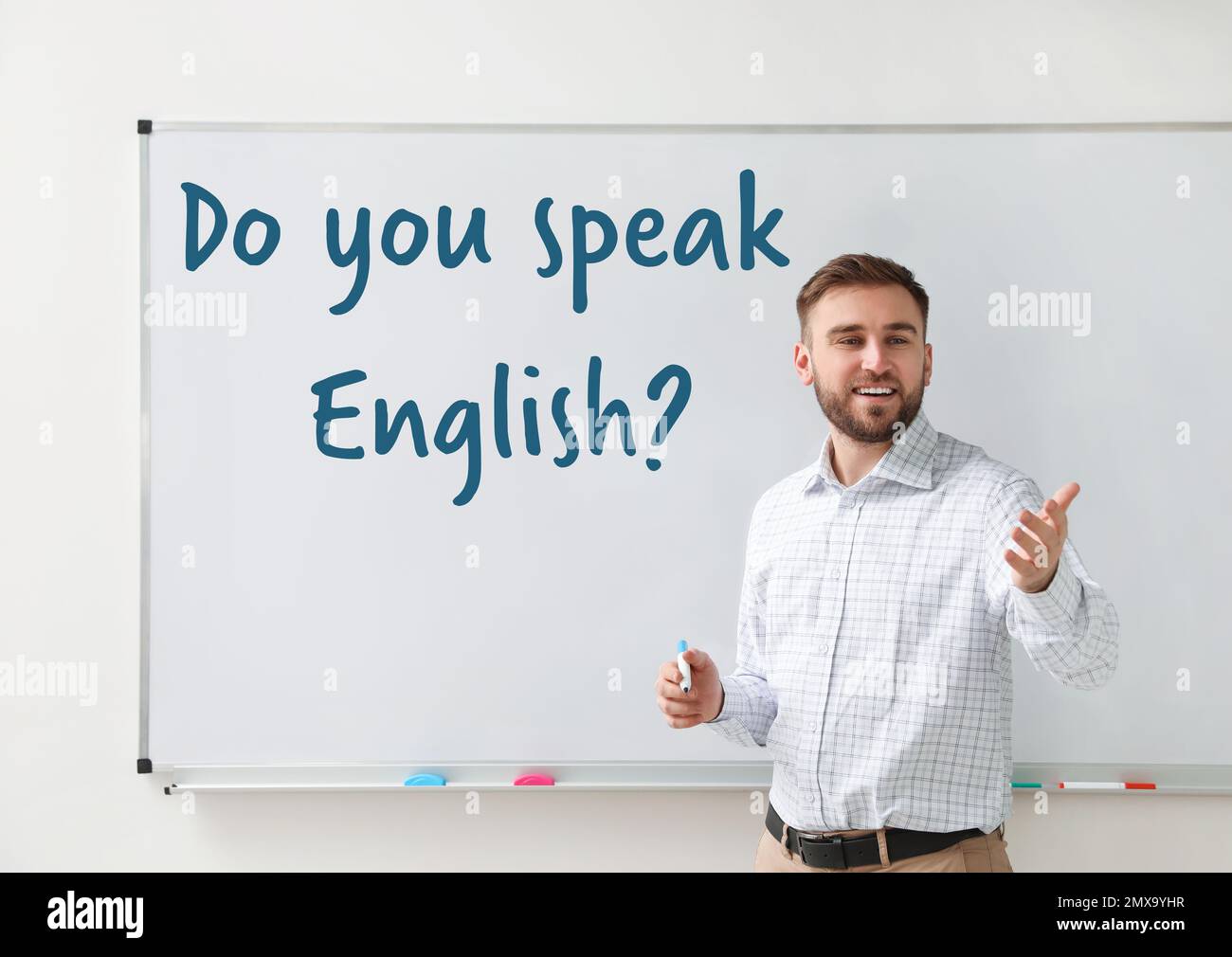 Junger Englischlehrer in der Nähe des Whiteboards im Klassenzimmer Stockfoto