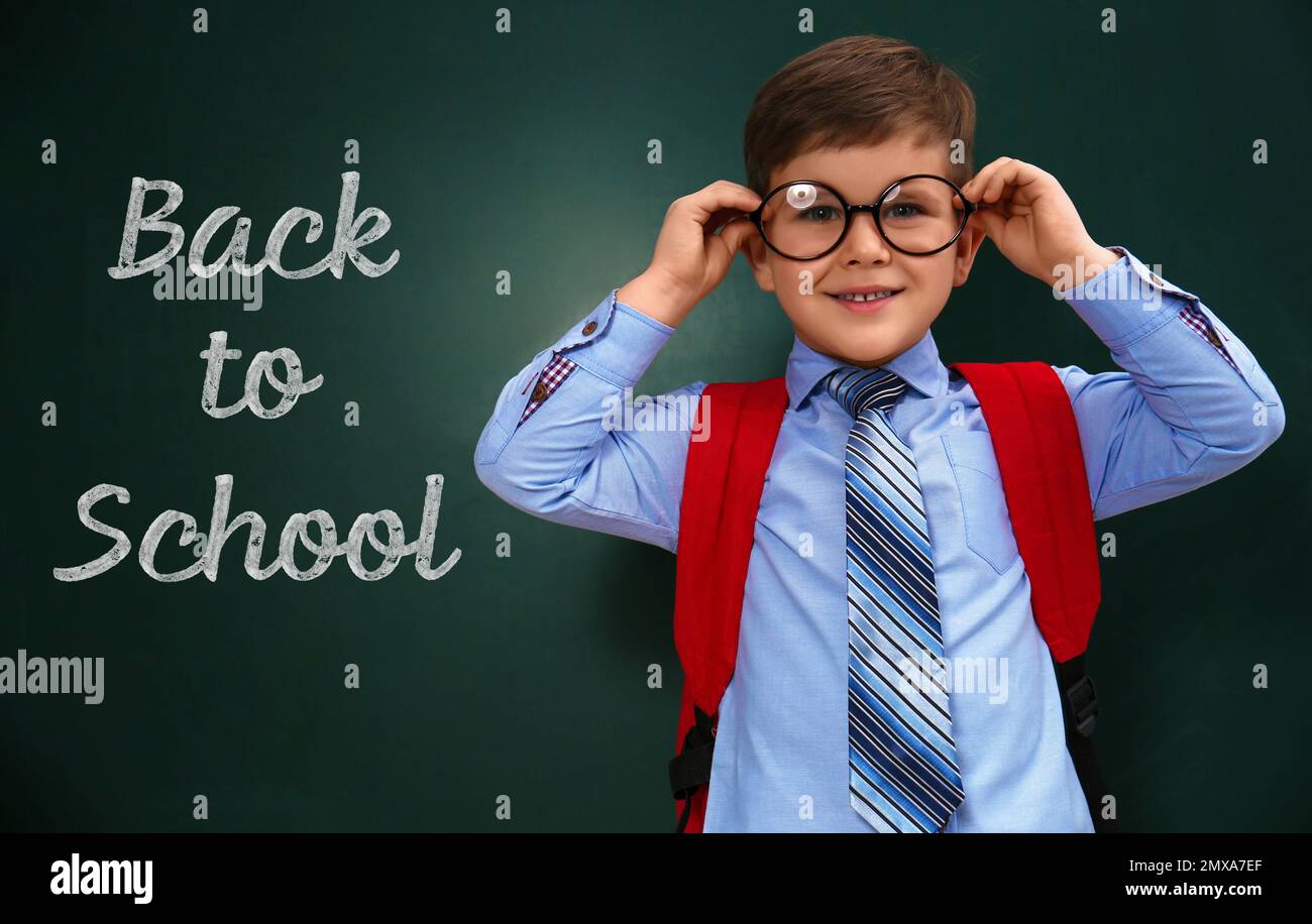 Süßes kleines Kind, das eine Brille in der Nähe einer Tafel trägt, mit  Phrase ZUR SCHULE Stockfotografie - Alamy