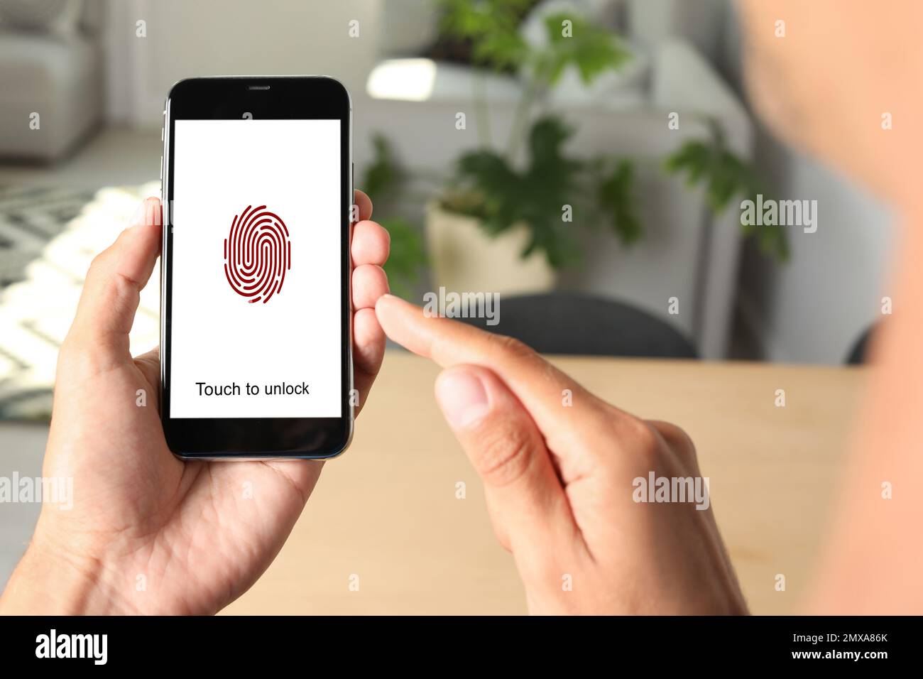 Mann mit Smartphone und Fingerabdrucksensor in Innenräumen, Nahaufnahme. Digitale Identität Stockfoto