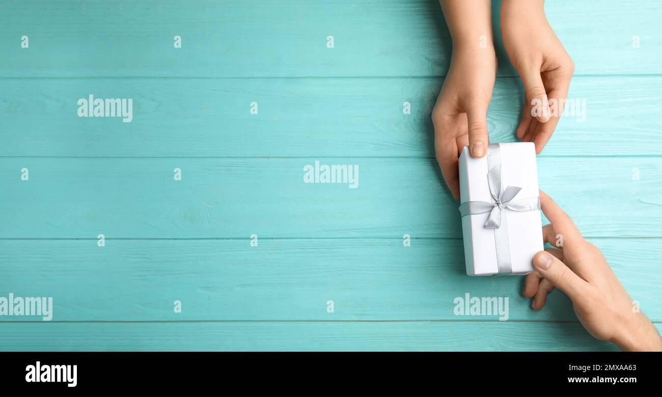 Personen mit Geschenkbox und Platz für Text auf hellblauem Holzhintergrund, Draufsicht. Bannerdesign Stockfoto