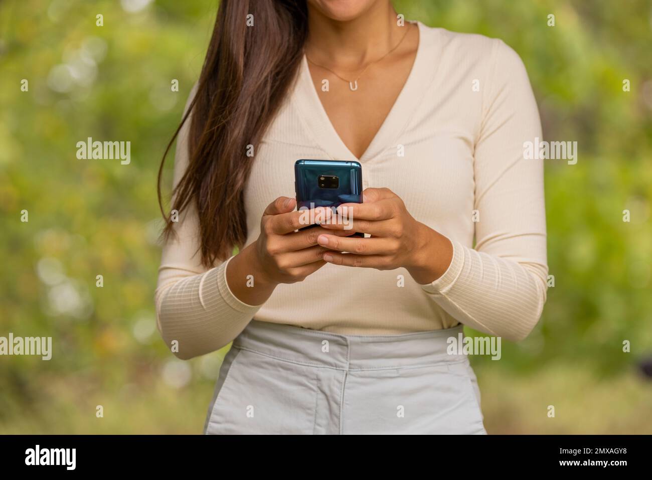 Frau, die beim Wandern im Wald mit der App für SMS-Nachrichten telefoniert. Nahaufnahme von Handy und Mittelteil. Nachhaltigkeit, Natur-Lebensstil Menschen Stockfoto