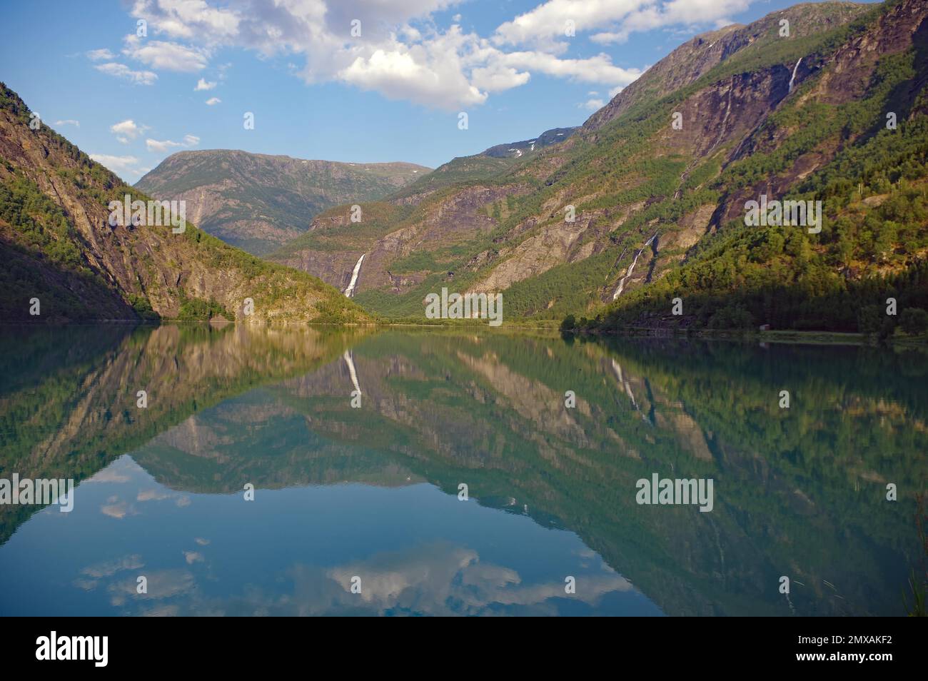 Berge und Wasserfall spiegeln sich in den ruhigen Gewässern eines Sees, Idylll, Skjolden, Westnorwegen, Norwegen Stockfoto