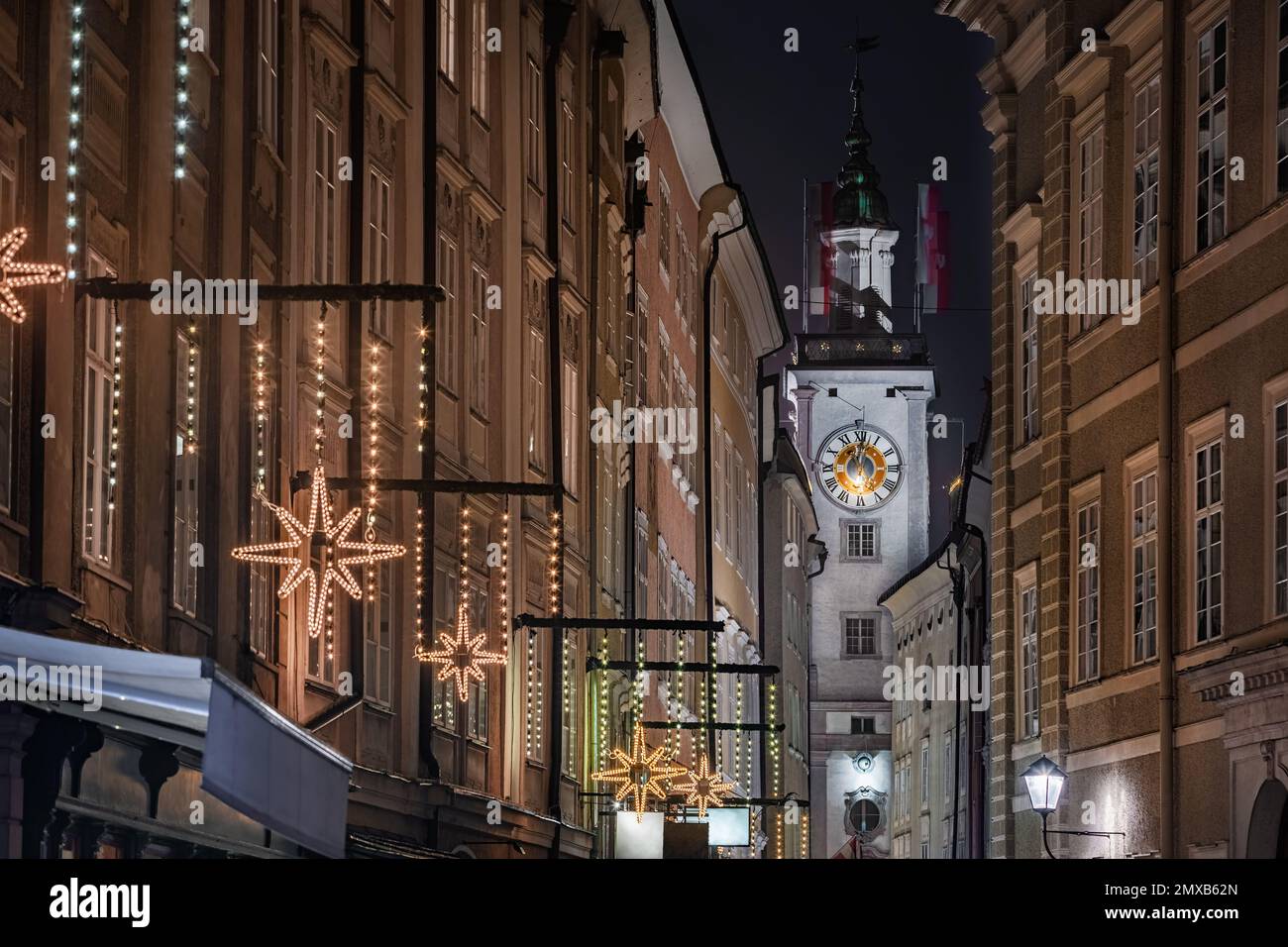 Salzburg, Österreich - beleuchteter Uhrenturm des ehemaligen Alten Rathauses an der weihnachtlich dekorierten Getreidegasse, der berühmten Einkaufsstraße Stockfoto