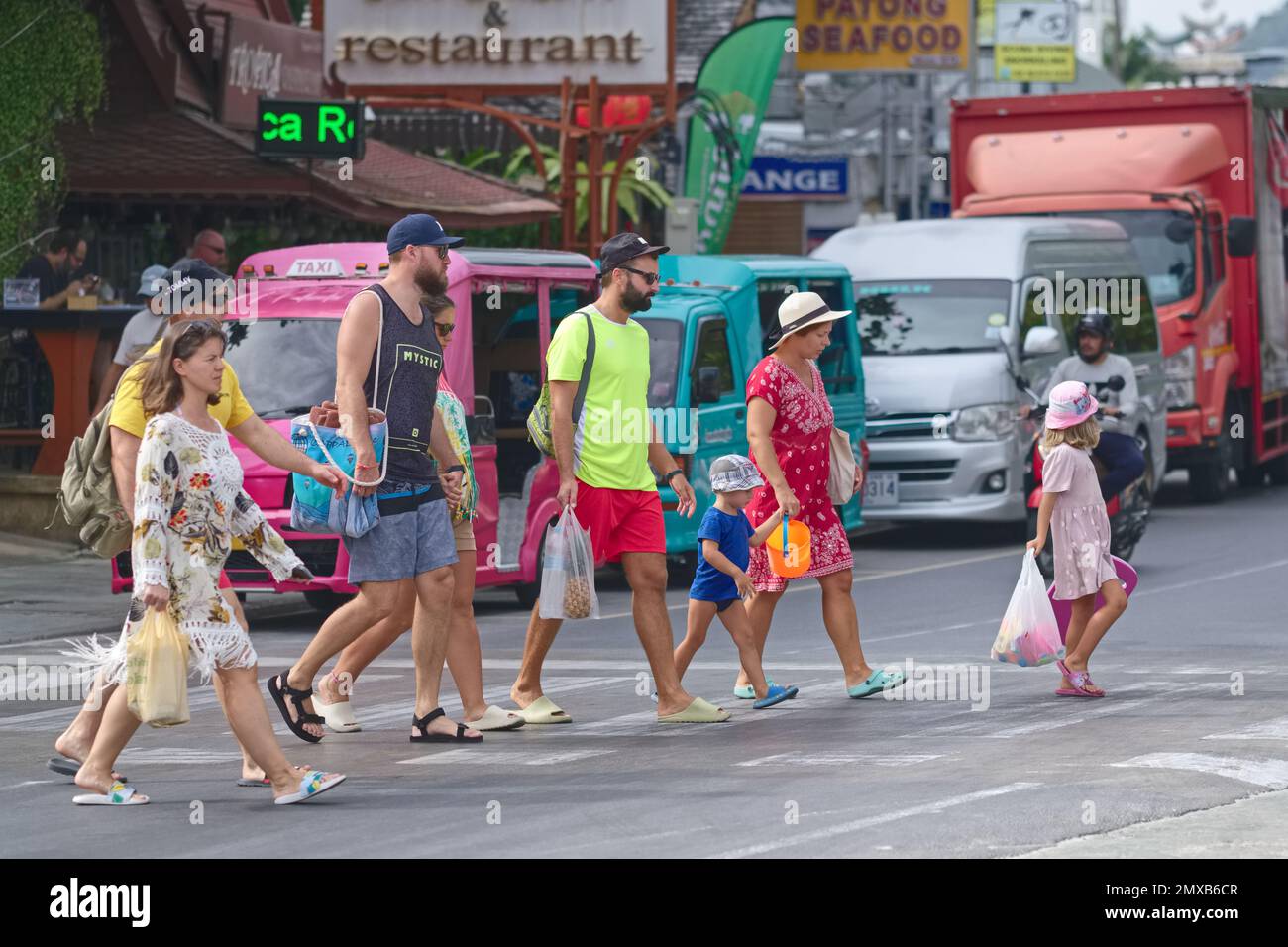 Ausländische Touristen mit Kindern in Patong, Phuket, Thailand, Südostasien, die die Straße mit einem Zebra überqueren Stockfoto