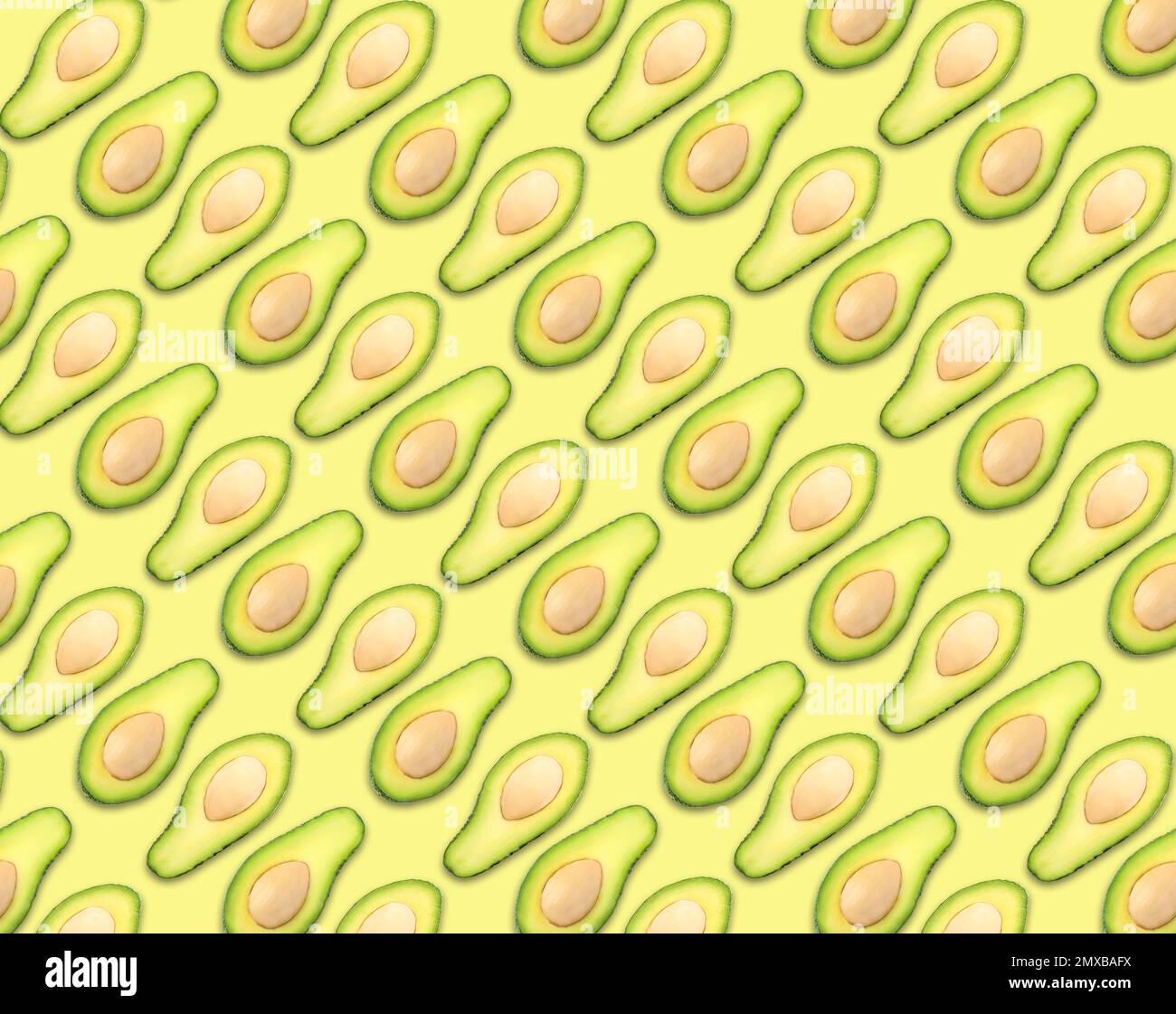 Muster der Avocadahälften auf blassgelbem Hintergrund Stockfoto