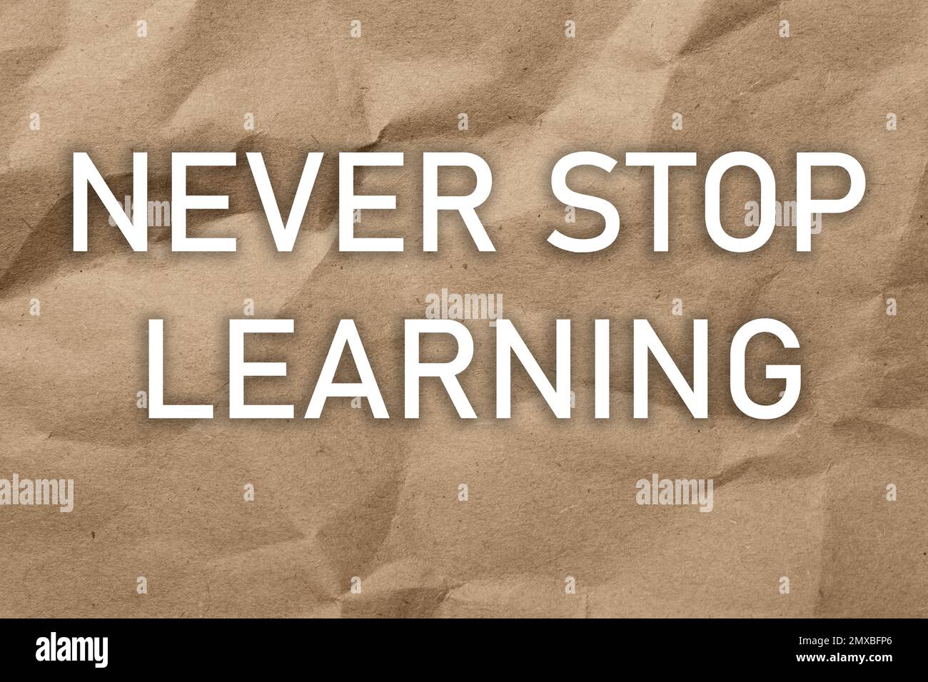 Auf braunem, zerknittertem Papier LERNT man IMMER WIEDER Stockfoto