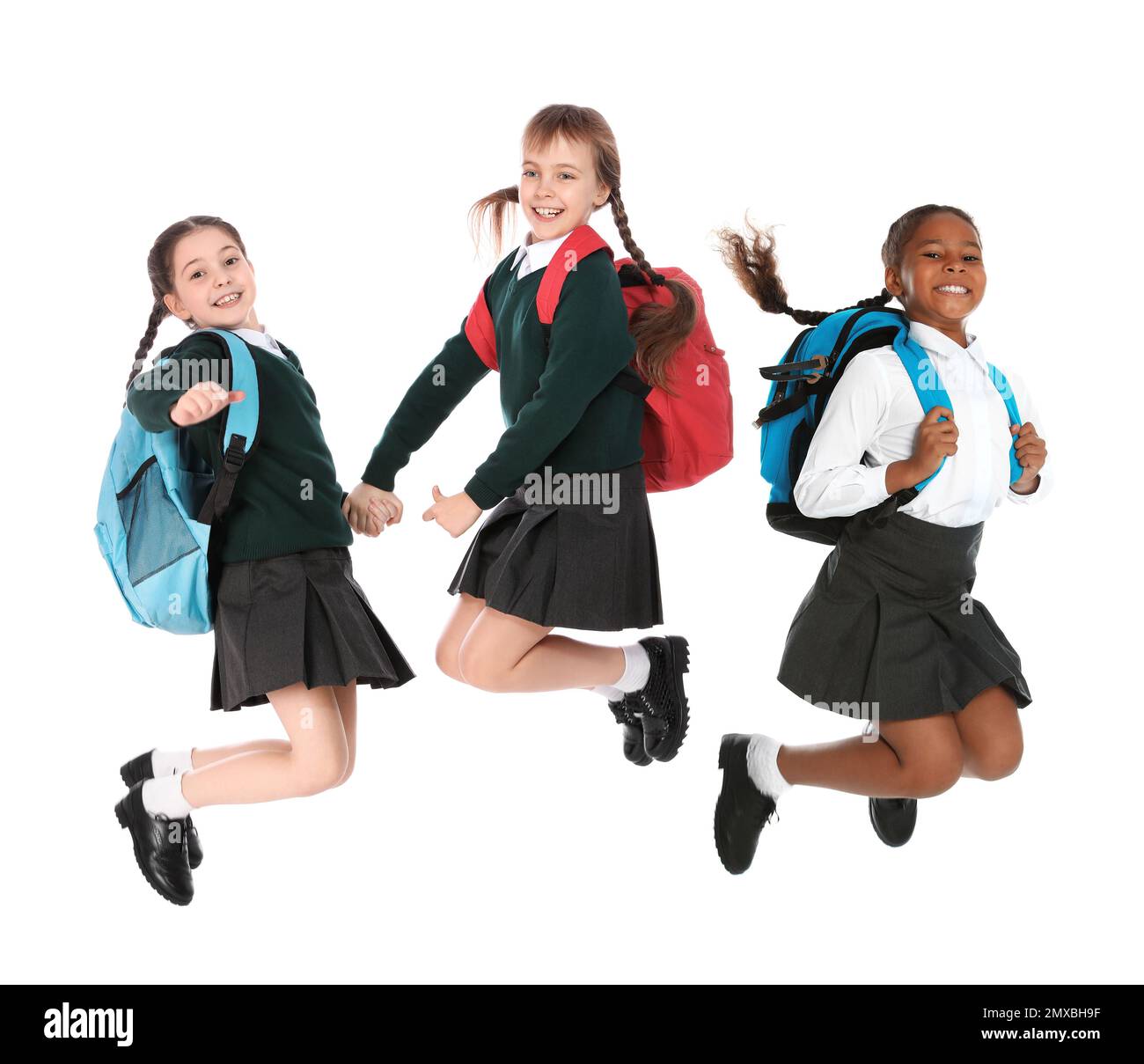 Kinder in Schuluniform springen auf weißem Hintergrund Stockfoto