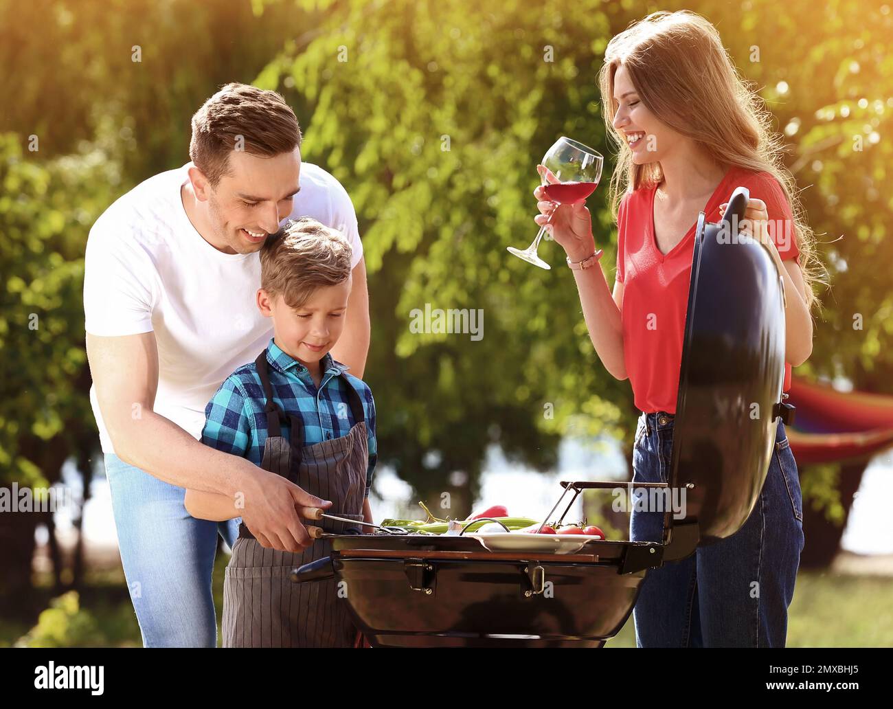 Glückliche Familie mit Grill mit modernen Grill im Freien Stockfoto