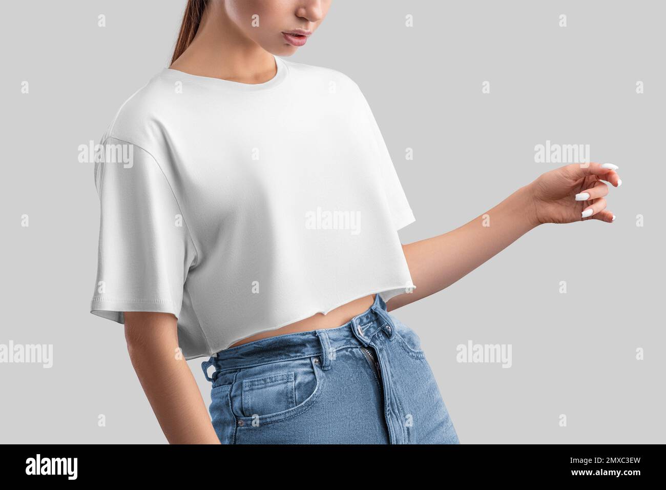 Weißes Crop-Top-Modell von positivem Mädchen in Jeans, isoliert im Hintergrund, Vorderansicht. Freischnitt-Kleiderschablone, leeres übergroßes T-Shirt, Hemd für Desi Stockfoto