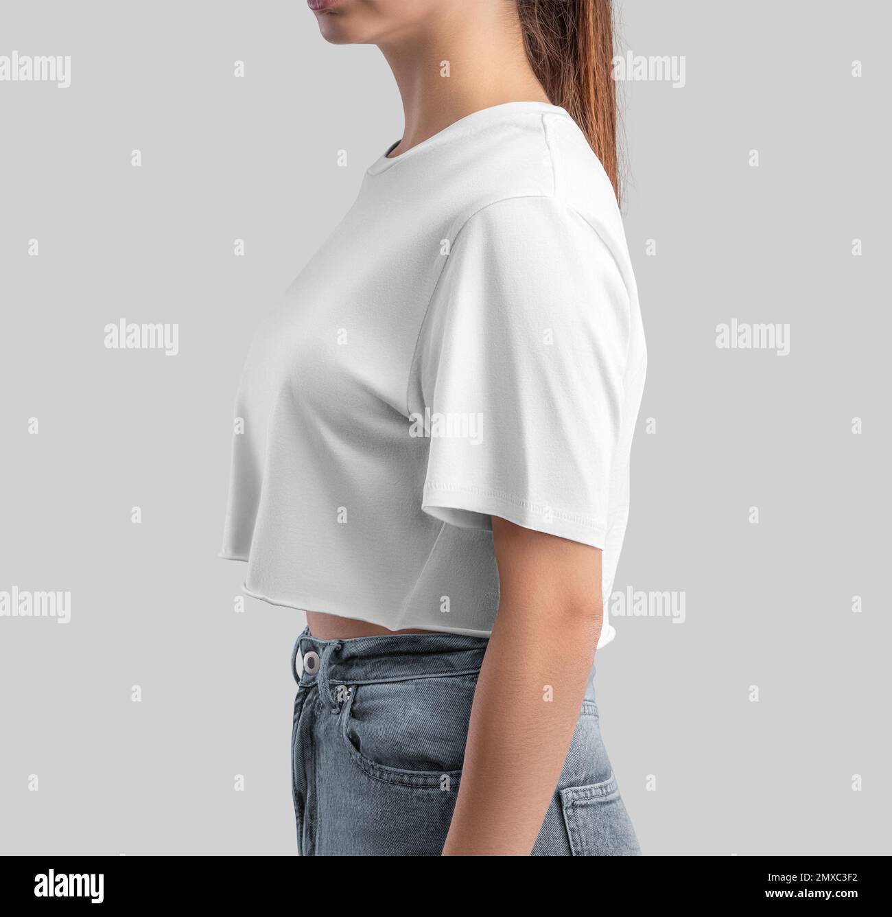 Weiße T-Shirt-Vorlage, Crop Top auf einer schlanken Frau in Jeans, isoliert im Hintergrund, Seitenansicht. Modehemd für Design, Druck, Marke, Werbung. T-sch Stockfoto