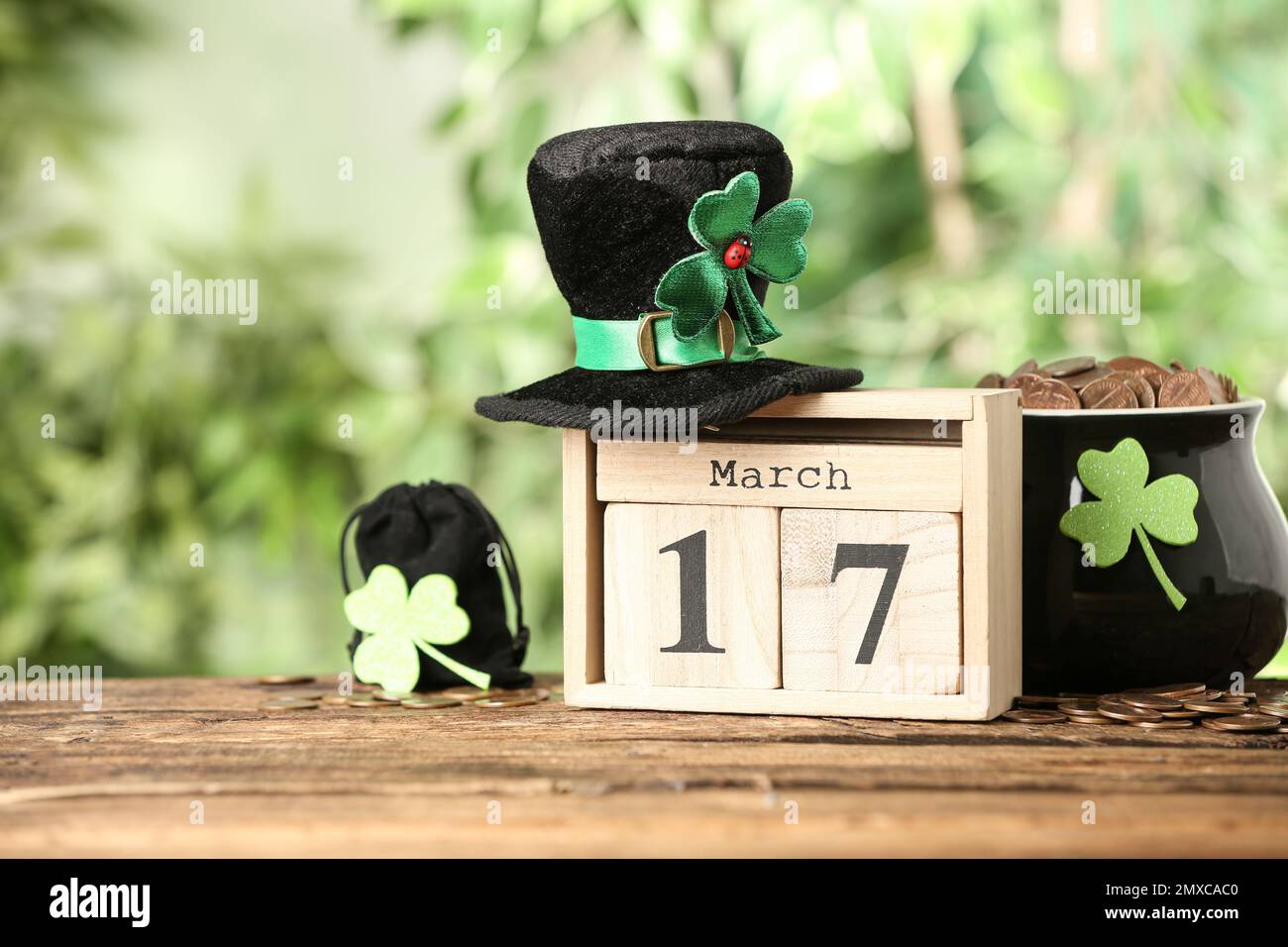 Komposition mit Blockkalender auf Holztisch gegen verschwommenes Grün. St. Patrick's Day-Feier Stockfoto