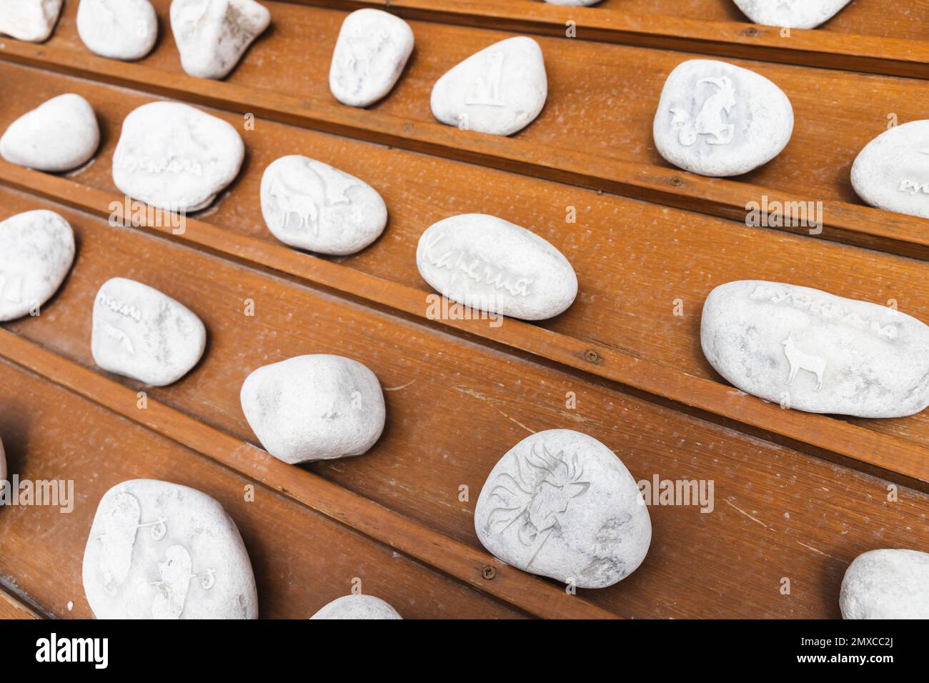 Ruskeala, Russland - 12. Juni 2021: Weiße Marmorsteine mit dekorativen Schnitzereien lagen auf einer hölzernen Theke mit Souvenirläden. Text steht für Ruskeala-Städtename Stockfoto