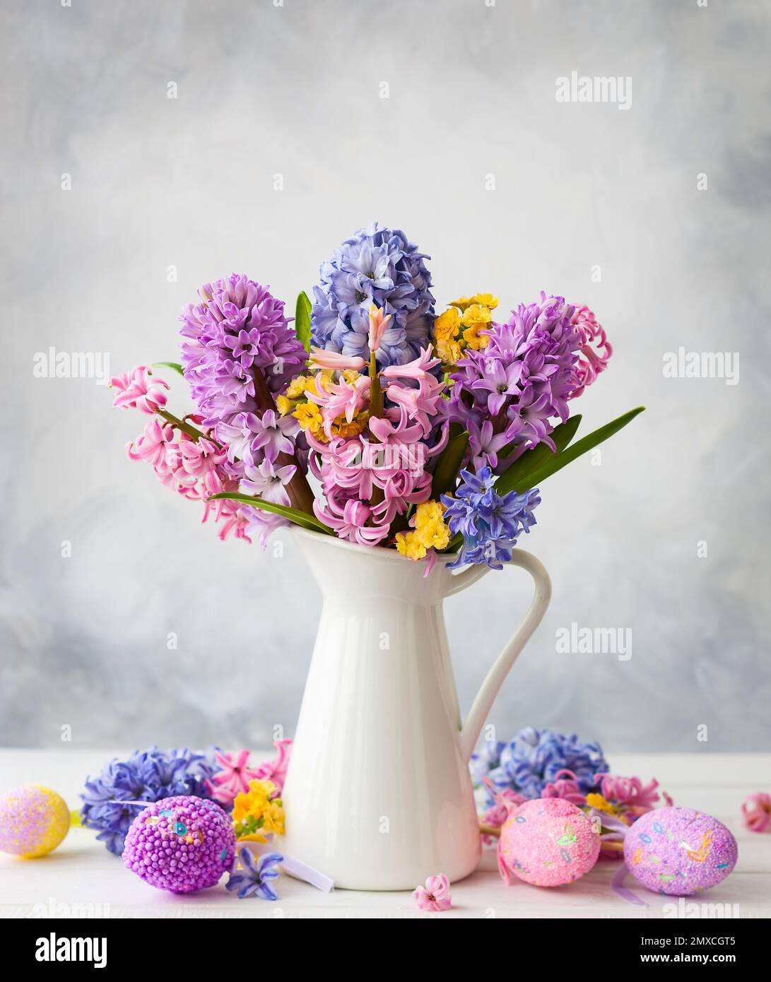 Osterstille Leben mit Flieder und rosa Hyazinthen und Ostereiern auf weißem Tisch Stockfoto