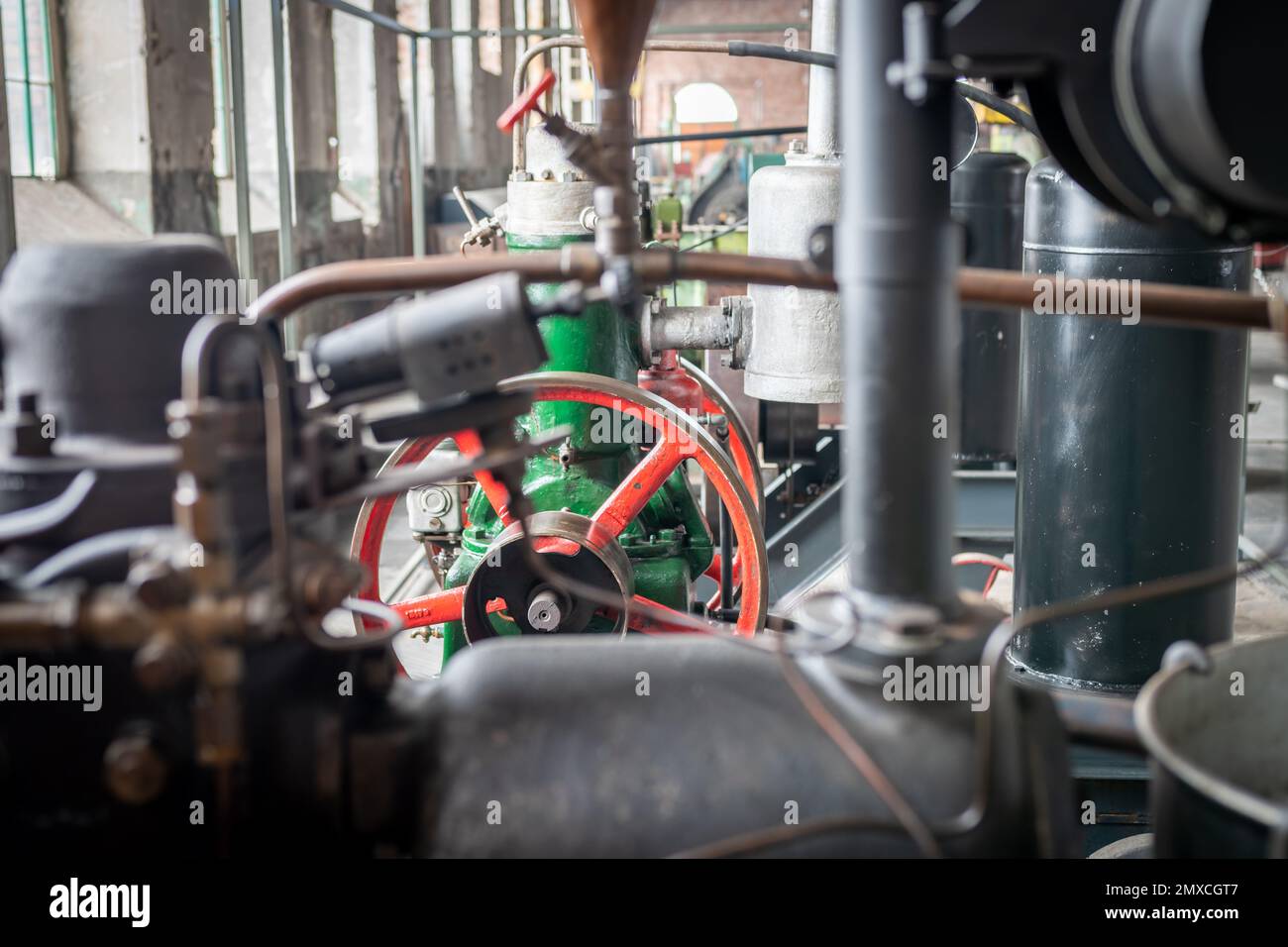 Altmodische Maschinen in einer alten Fabrikeinrichtung. Industriemotoren. Rohre, Getriebe, Ventile und andere Teile. Stockfoto